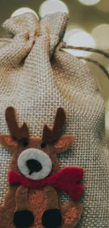 Hand holding a burlap bag with a reindeer design.