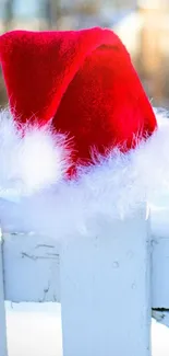 Red Santa hat resting on a snowy white fence