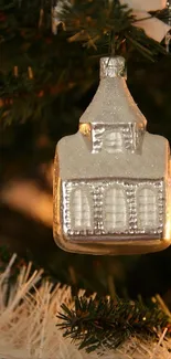 Silver ornament hanging on a Christmas tree branch, glittering among green needles.