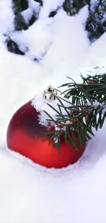 Red Christmas ornament in snowy pine branches, perfect holiday wallpaper.