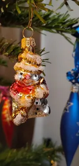 Festive snowman ornament hanging on a decorated Christmas tree branch.