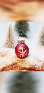 Red Christmas ornament on snow-covered branch in winter scene.