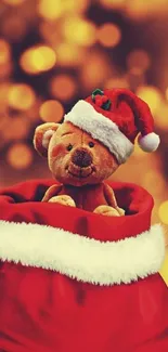 Teddy bear in Santa hat with red sack and warm bokeh background.