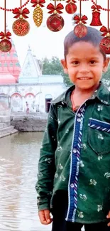 Smiling child in front of vibrant temple with festive ornaments.