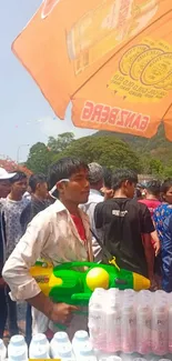 Outdoor water festival with orange umbrella and festive crowd.