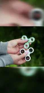 Hands holding a green fidget spinner against a blurred background.