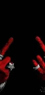 Red hands with jewelry against black background.