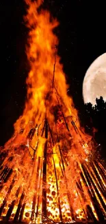 Bonfire blazing under a full moon in the night sky.