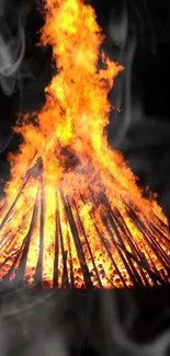 Bonfire with intense flames and smoke at night.