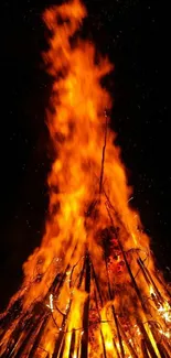 Tall bonfire with vivid orange flames at night.