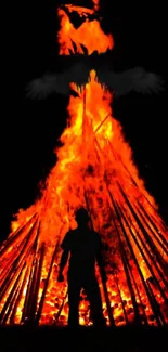 Silhouette against a fiery bonfire with a mysterious flying figure.