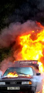 Burning car with intense flames and smoke on a mobile wallpaper.