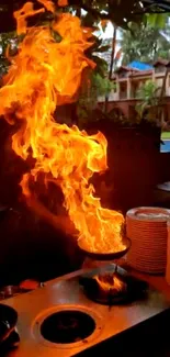 Flame engulfed pan in outdoor kitchen setting with bright orange fire.