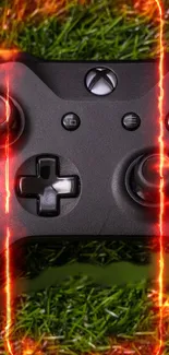 Black gaming controller with fiery effects on grass background.