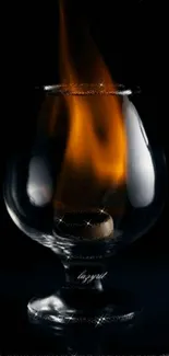 Glass with a bright flame against a dark backdrop.