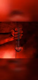 Fist holding a fiery red heart pendant in dark background