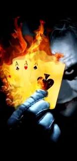 Joker holding flaming playing cards in the dark.