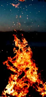 A blazing orange campfire with sparks against a dark night sky.