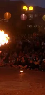 Street fire performer mesmerizing crowd at night.