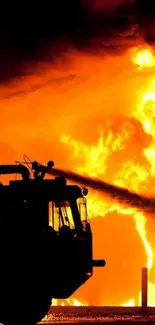 Silhouette of a fire truck against intense orange flames.