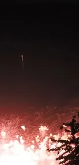 Fiery rocket launch illuminating the night sky with vibrant red-orange glow.