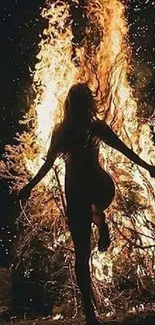 Silhouette dancing by a bright bonfire at night.