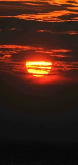 Fiery sunset over ocean horizon with vibrant orange and red hues.