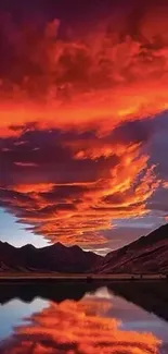 Fiery sunset over mountains with lake reflection.