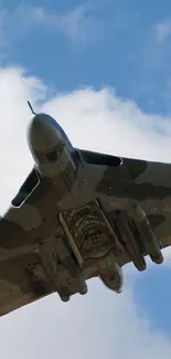 A fighter jet soaring through a clear blue sky with white clouds.