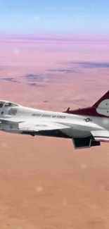 Fighter jet flying over a vast desert landscape.