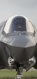 A sleek fighter jet on the runway with a cloudy sky background.