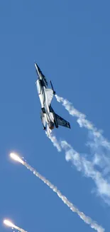 Fighter jet soaring in blue sky with contrails and flares.