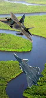 Two fighter jets flying over a lush green landscape with a winding river.