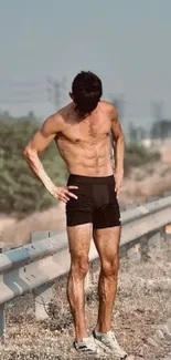 Man exercising on a scenic roadside with nature in the background.