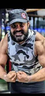 Man flexing muscles in gym with camo tank-top.