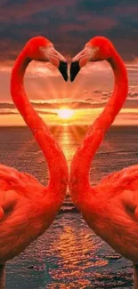 Two flamingos form a heart at sunset over the ocean.