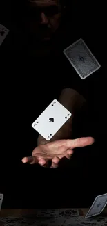 Floating playing cards in a dark setting with a hand.