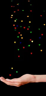 Hand catching colorful floating hearts on black background.