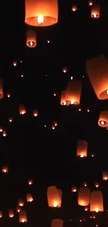 Floating lanterns illuminating a dark night sky.