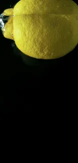 Vibrant yellow lemon floating in dark water background.