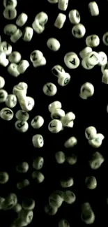 Floating letter beads on a black background, creating an artistic and abstract wallpaper.