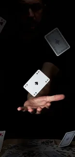 A hand extends under floating playing cards on a black background.