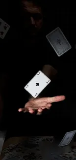 Mysterious hand with floating playing cards on a dark background.