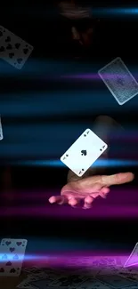 Hand with floating playing cards in a dark setting.