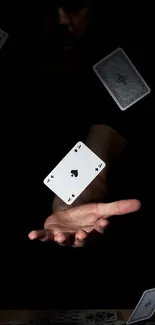 Floating playing cards on a dark background with a mysterious hand.