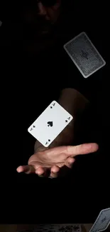 Floating playing cards hover over an open hand in a dark theme wallpaper.