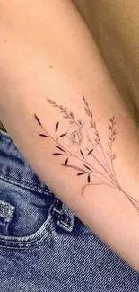 Floral arm tattoo with botanical line art on a beige background.