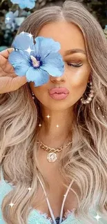 Woman with blue hibiscus flower by her eye, surrounded by floral beauty.