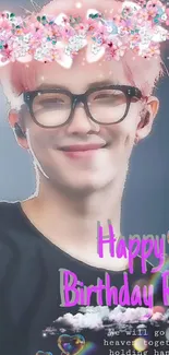 Smiling figure with pink floral crown and birthday text on phone wallpaper.