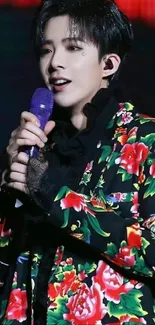 Singer with floral jacket on stage holding a microphone.